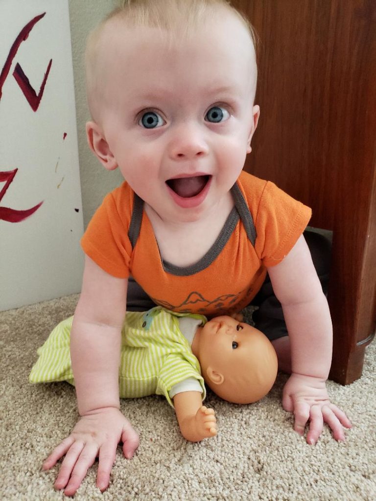 Baby brother playing with a baby doll wearing a DIY sleep sack.