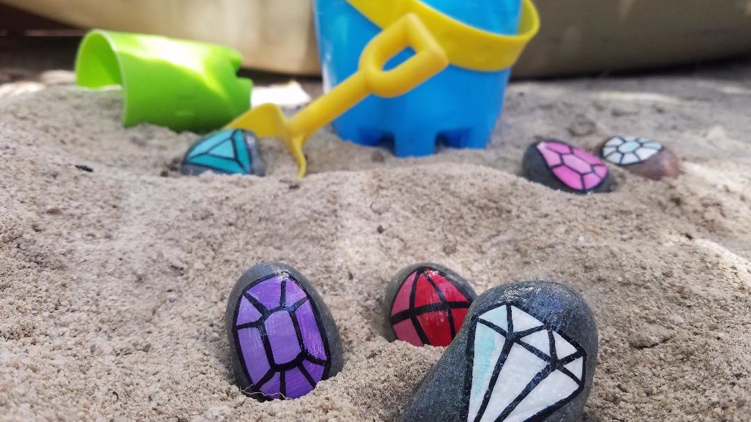 Hand painted gems on stones for kids to burry and find in the summer sandbox.